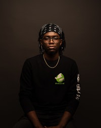 a black man with dreadlocks sitting on a black background