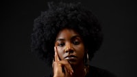 a black woman with an afro is posing with her hand on her chin