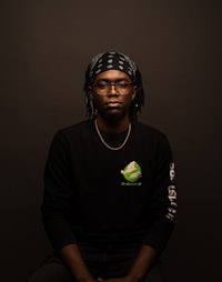 a black man with dreadlocks sitting on a black background