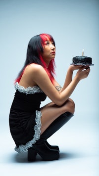 a woman in a black dress holding a cake